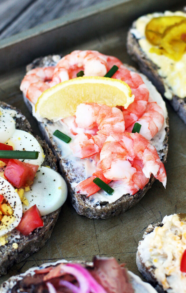 Open-faced sandwiches with fresh shrimp, chives, and lemon wedges.